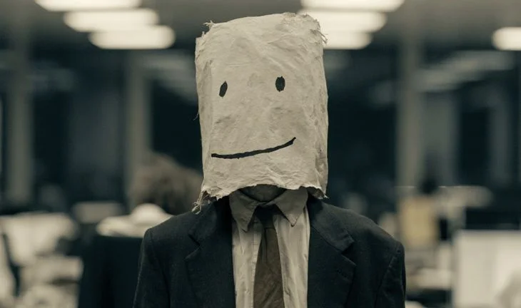 a banker with a bag over his head. the bag has a face on it