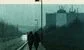 two people walking in the rain along a dismal road